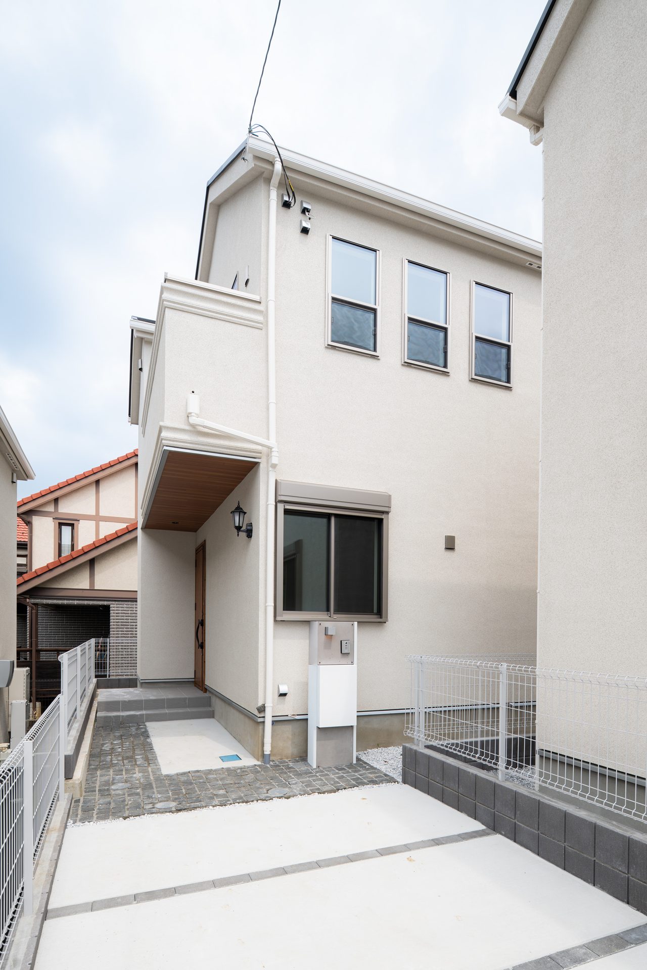 木目調の軒天と玄関ドアが見える2階建ての外観